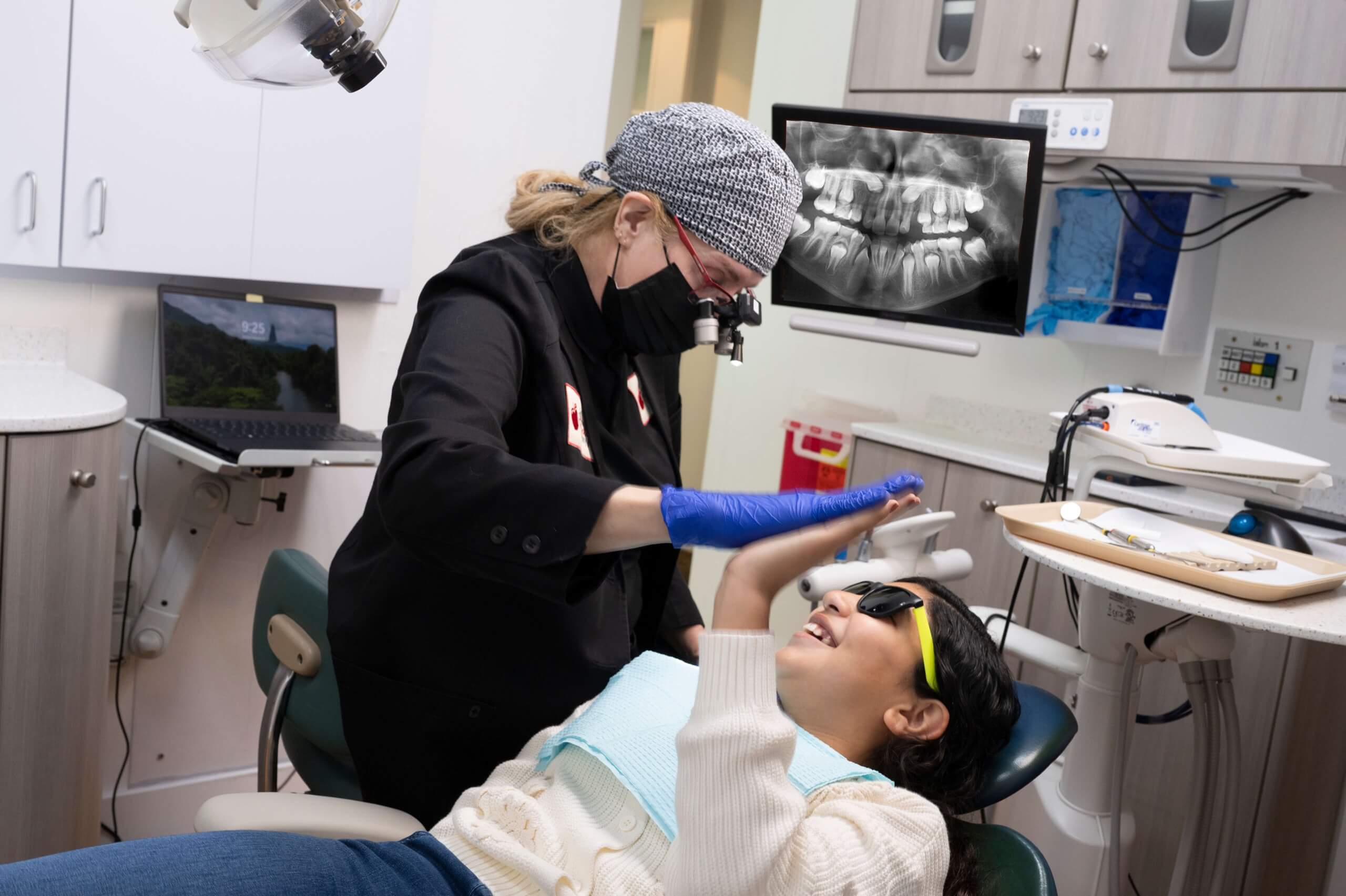 A dentist reassures a patient during an exam with digital X-ray equipment, reflecting the gentle urgent care approach at San Anselmo Family Dentistry.